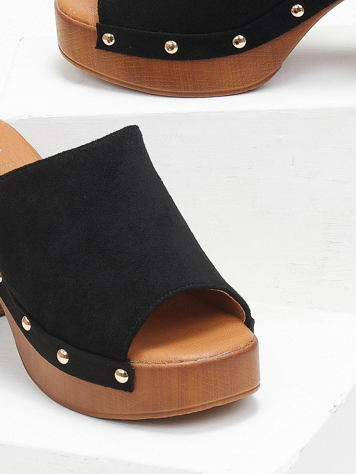 Close-up of black suede block heel slide with gold studs and wooden-look platform, angled top view on a white background