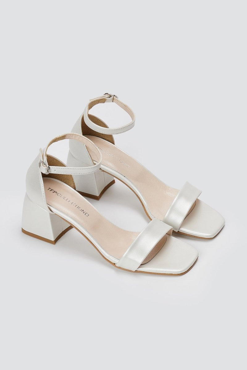 Pair of metallic silver leather block heel sandals with ankle straps and square open toes, angled view on a light grey background