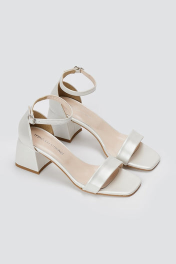 Pair of metallic silver leather block heel sandals with ankle straps and square open toes, angled view on a light grey background
