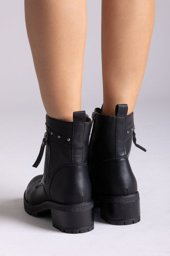 Model legs in black leather lace-up ankle boots with chunky block heels and side zip, front view on a light backdrop