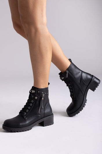 Model legs in black leather lace-up ankle boots with chunky lug soles, angled view on a light backdrop