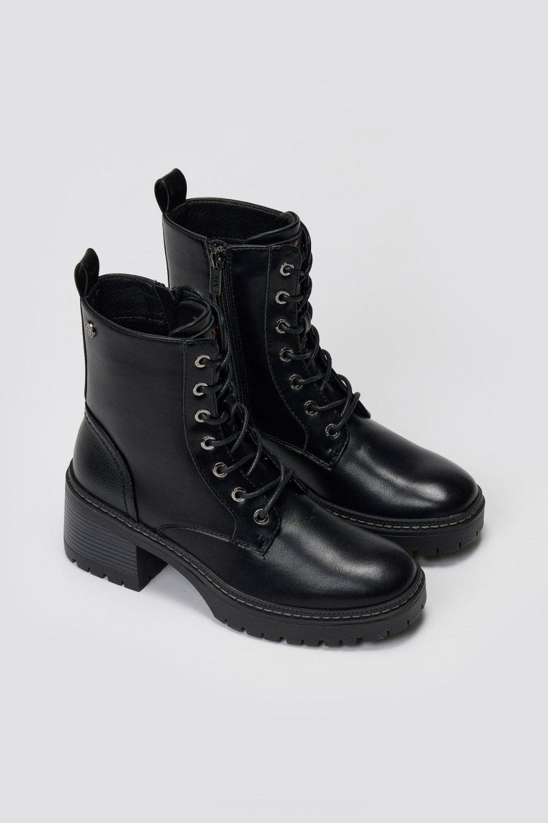 Pair of black leather lace-up ankle boots with chunky lug soles, angled view on a light grey background