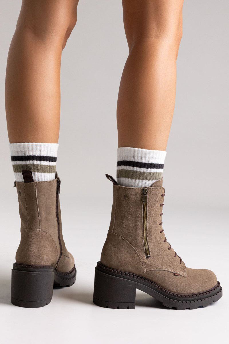 Model legs in taupe suede lace up boots with block heel and striped socks, front view on light grey background