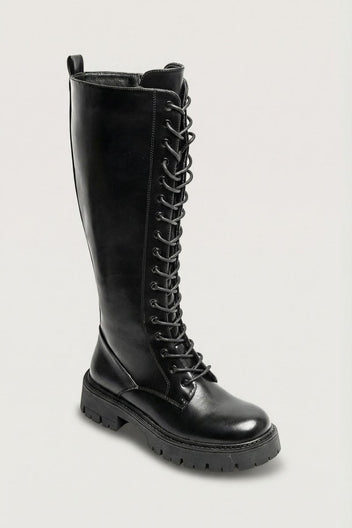Black leather knee-high lace-up boot with chunky lug sole, angled view on a light grey background