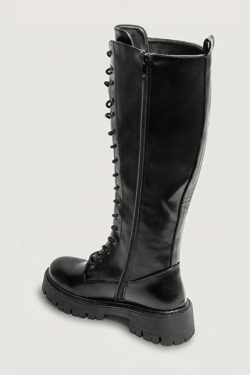 Black leather knee-high lace-up boot with chunky lug sole and side zip, angled view on a light grey background
