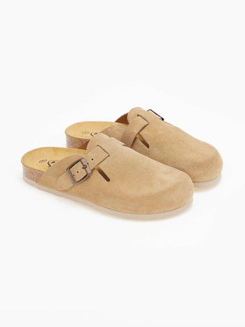 Pair of beige suede clogs with buckle straps and cork footbeds seen at an angle on white surface