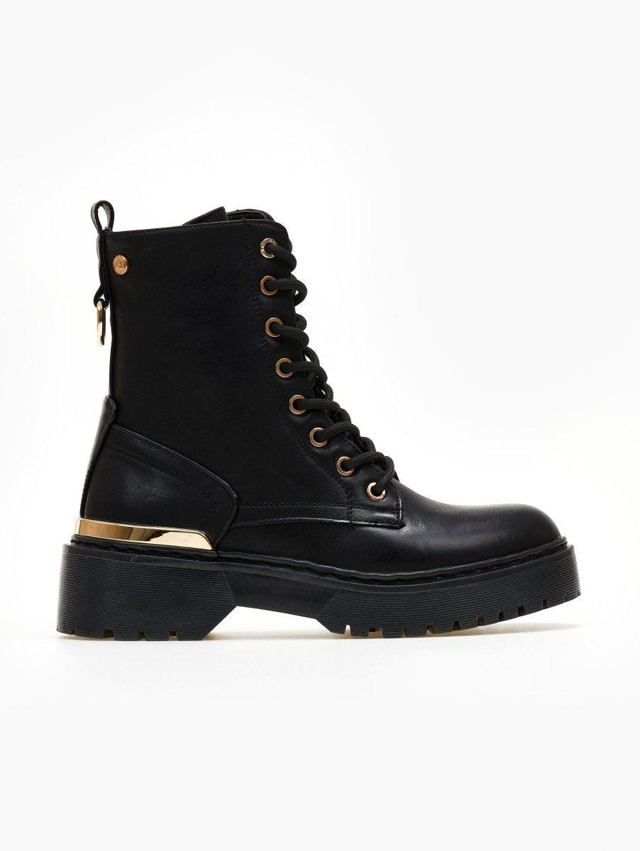 Black lace-up ankle boot with gold eyelets, gold metal trim and chunky black sole on a white background