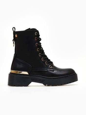 Black lace-up ankle boot with gold eyelets, gold metal trim and chunky black sole on a white background