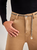 Close-up of beige high-waisted wide leg jeans with silver chain belt and heart charm, worn on model, front detail view