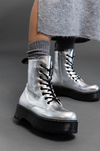 Model wearing silver metallic lace-up boots with black chunky sole over grey knit socks and a grey skirt