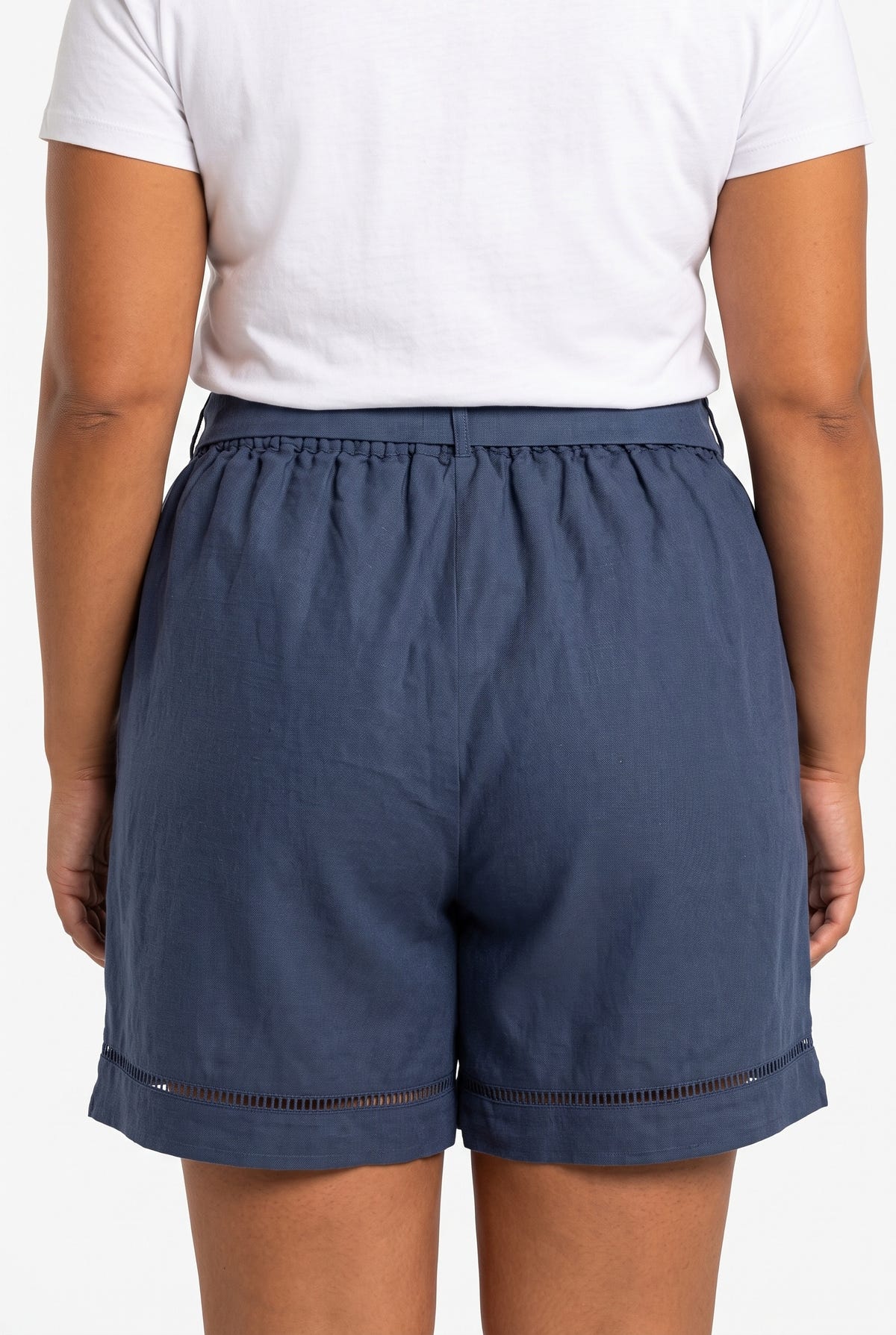 Model seen from behind wearing dark blue linen blend shorts with lace trim hem and white t-shirt