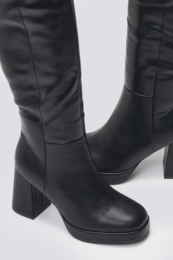 Close-up of black leather knee-high platform boots with block heels, detail of the rounded toe and sole