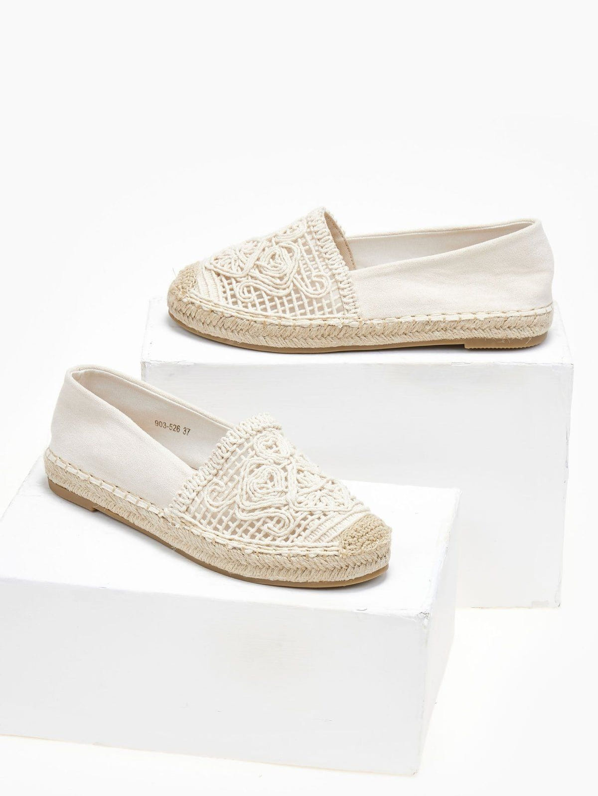 Pair of cream canvas espadrilles with openwork crochet vamps and jute soles resting on white blocks