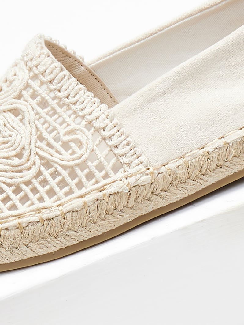 Close-up of cream crochet lace vamp and braided jute edge on a flat canvas espadrille shoe