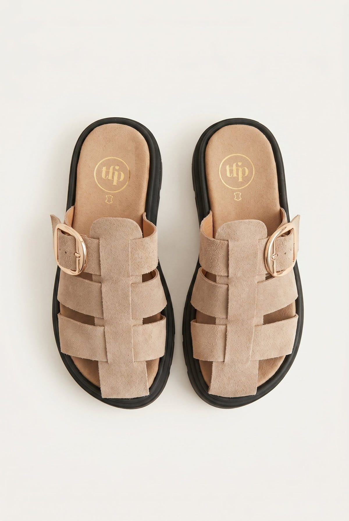 Overhead view of beige suede fisherman slides with caged straps, large gold buckles and chunky black soles
