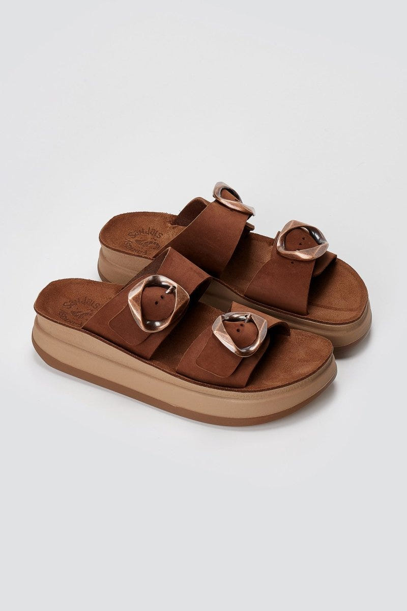 Brown suede flatform sandals with two straps and round buckles on thick tan sole, three-quarter view on light grey