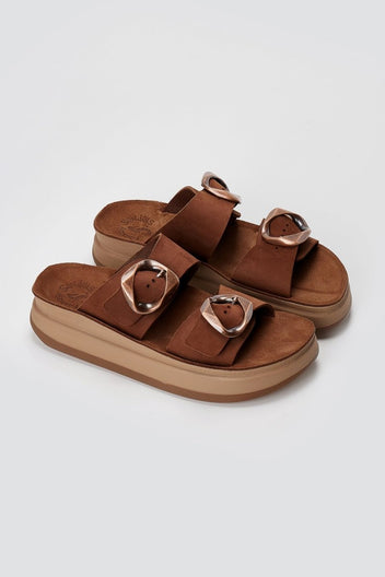 Brown suede flatform sandals with two straps and round buckles on thick tan sole, three-quarter view on light grey