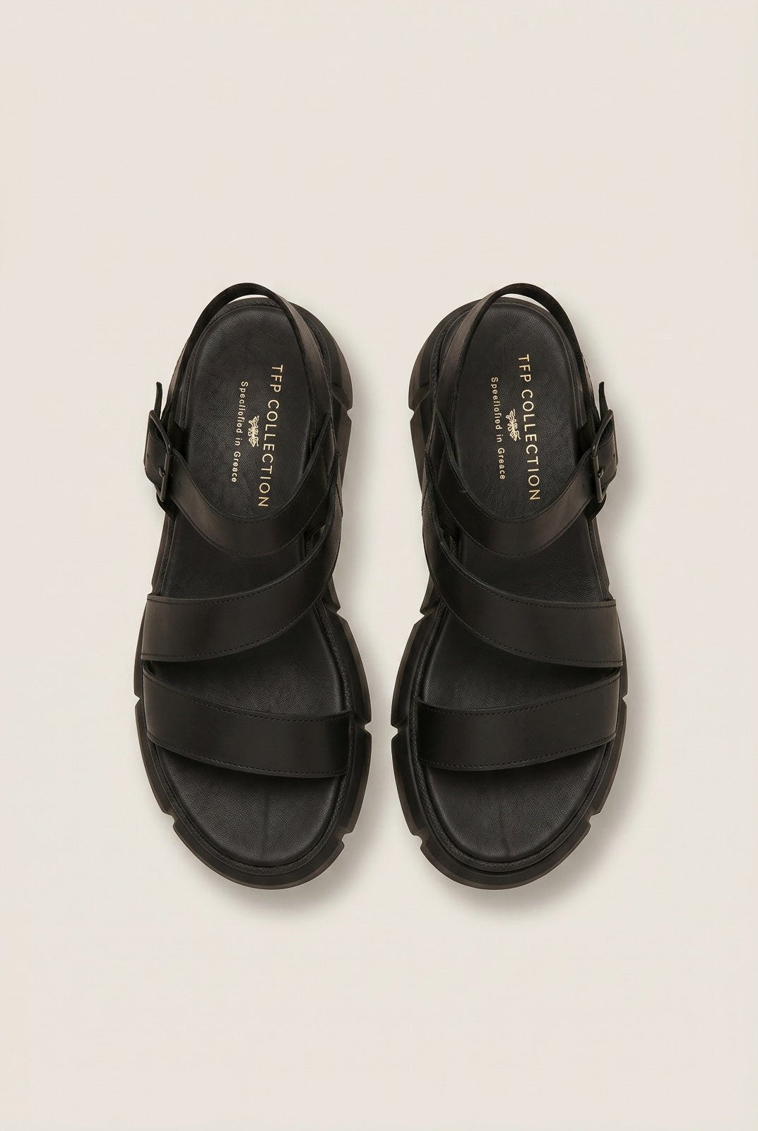 Overhead view of a pair of black leather flatform sandals with wide straps, ankle buckles and chunky soles