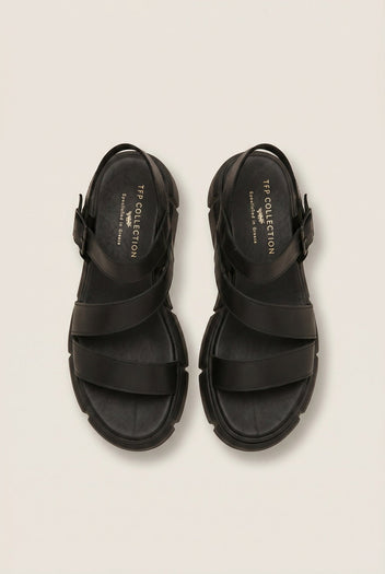 Overhead view of a pair of black leather flatform sandals with wide straps, ankle buckles and chunky soles