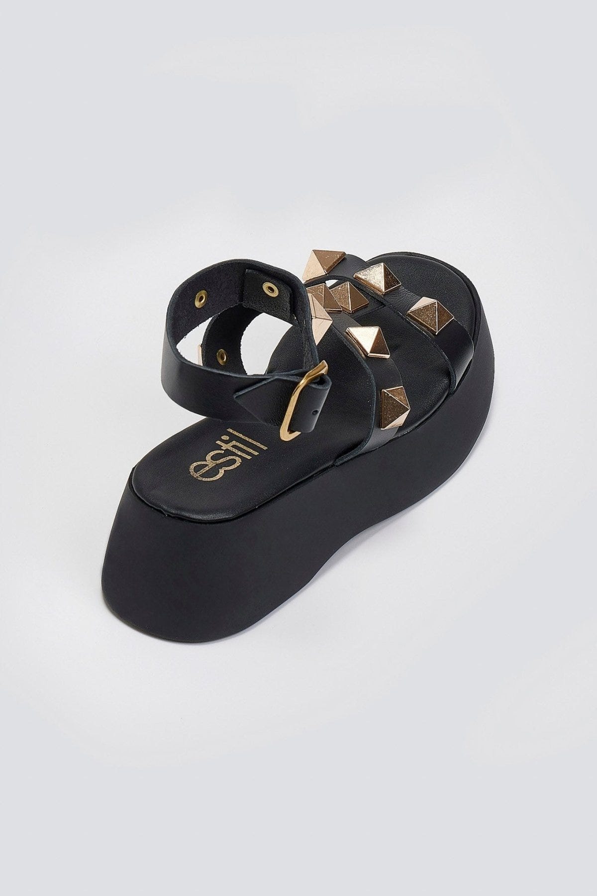 Black leather flatform sandal with gold pyramid studs, buckled ankle strap and thick platform sole, rear three-quarter view