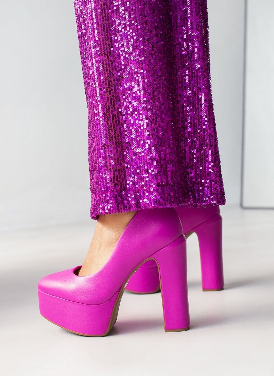 Fuchsia leather platform pump with thick block heel and round toe, worn on model, view from the back and side.