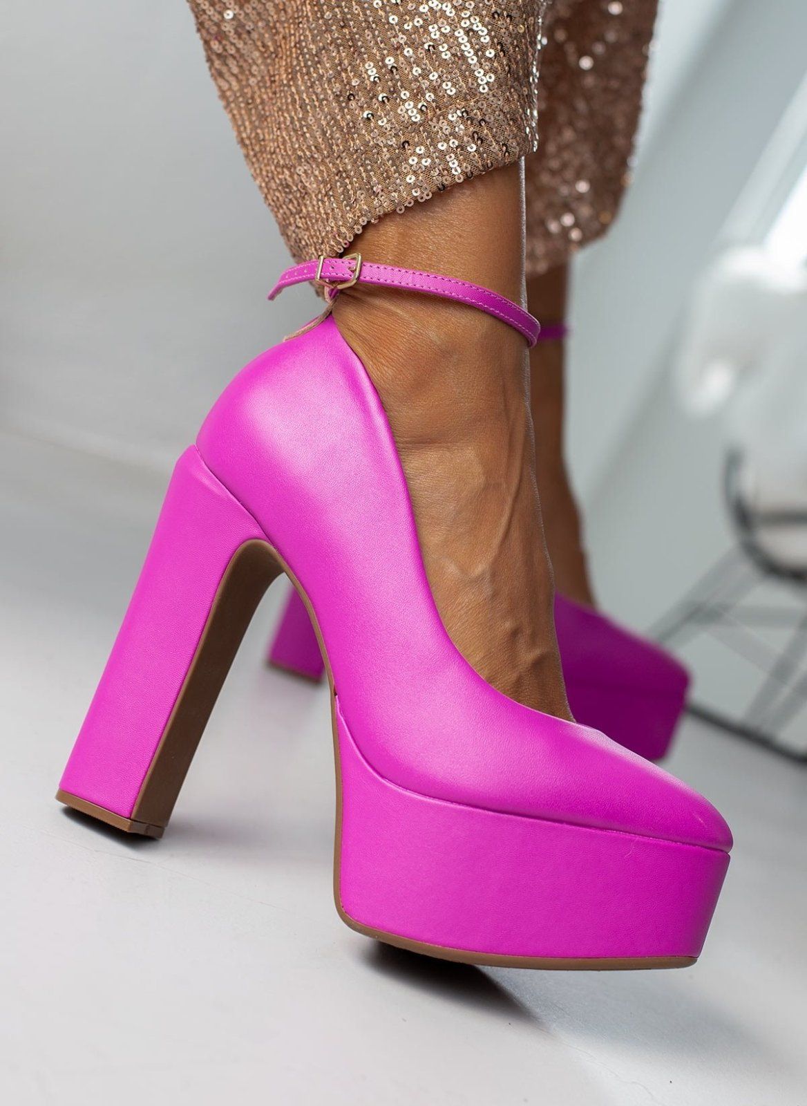 Fuchsia platform pump with chunky block heel and buckled ankle strap, worn on model, angled side view.
