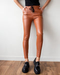 Rust-orange faux leather leggings with elasticated drawstring waist, front pockets and vertical front seams down each leg, worn on model, front view