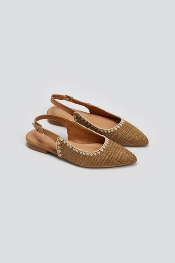Pair of tan woven raffia pointed toe flat slingbacks with cream trim and ankle straps, angled view