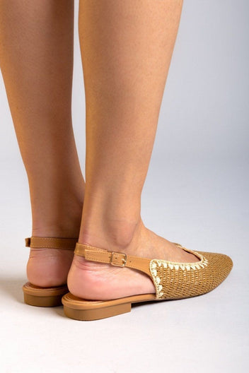 Rear view of model wearing tan woven raffia pointed toe slingback flats with cream trim and ankle straps