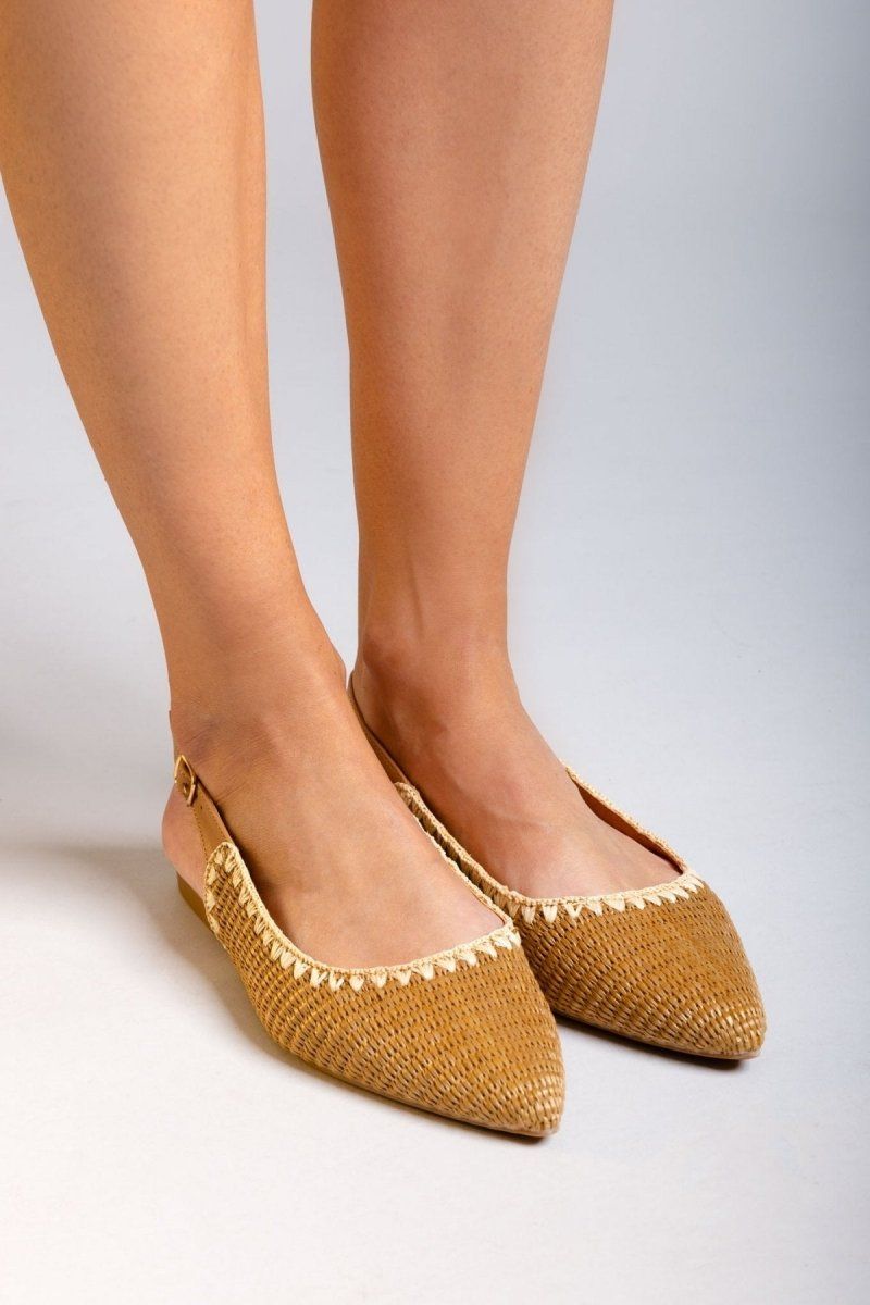 Model legs in tan woven raffia pointed toe slingback flats with cream trim, front view