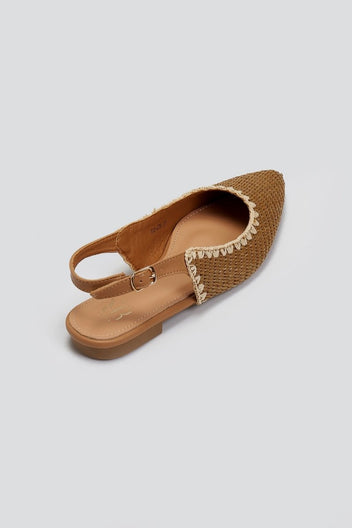 Tan woven raffia pointed toe flat slingback with cream trim and elastic ankle strap, angled rear view