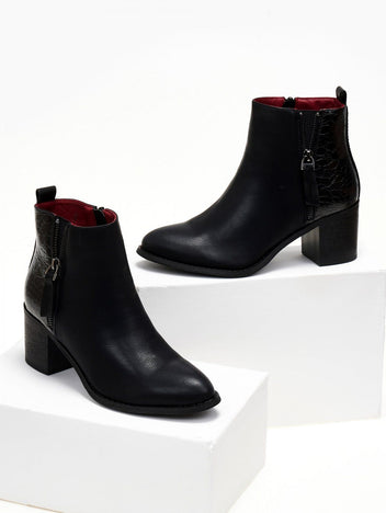 Black ankle boots with crocodile embossed panel and side zip with leather tassel, displayed on white blocks