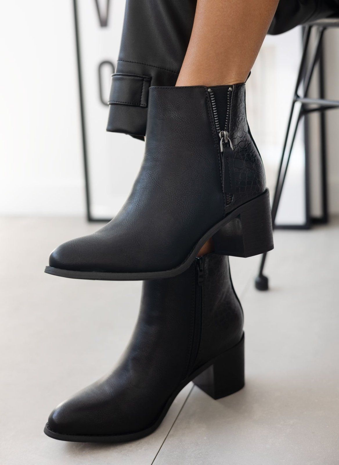 Black faux leather ankle boots with side zipper and block heel, worn on model, full length