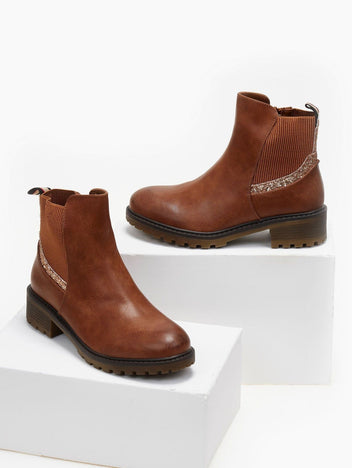 Pair of camel brown glitter-trim Chelsea ankle boots with low block heel, displayed on white blocks