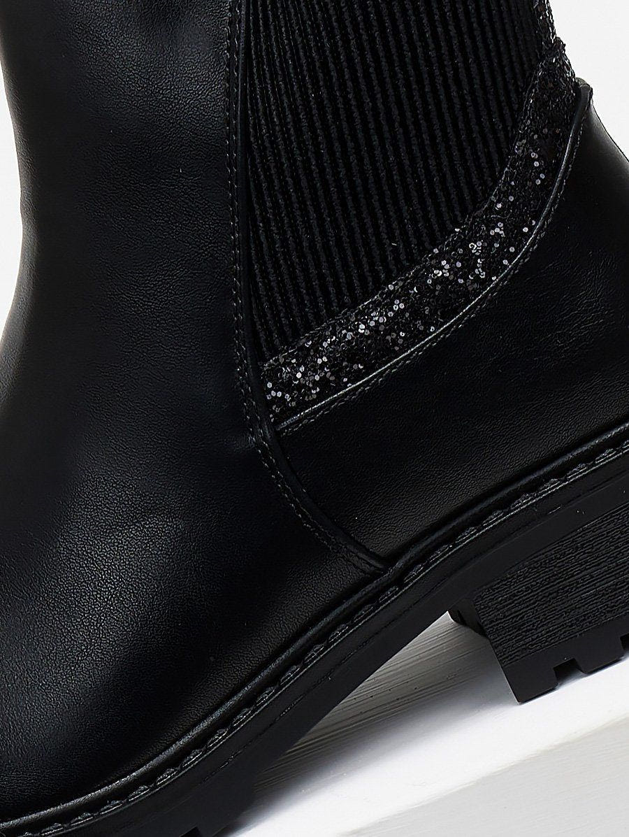 Close-up of black ankle boot elastic gusset with sparkling glitter trim and stitched leather detail