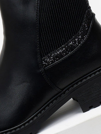 Close-up of black ankle boot elastic gusset with sparkling glitter trim and stitched leather detail