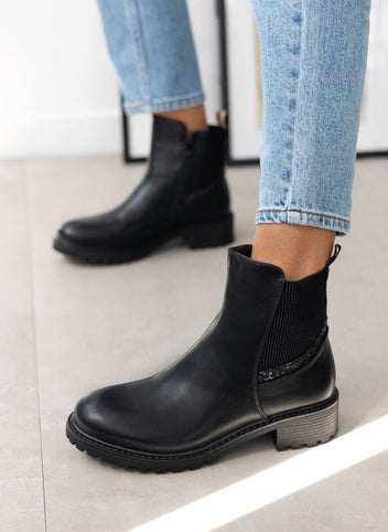 Black Chelsea ankle boots with glitter-trimmed elastic gusset and low block heel, worn on model, side view