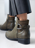Olive faux leather ankle boot with strap, silver ring buckle and suede-look panel, worn on model, back three-quarter view