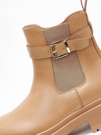 Close-up of taupe leather-look ankle boot with gold buckle strap and elastic side panel detail