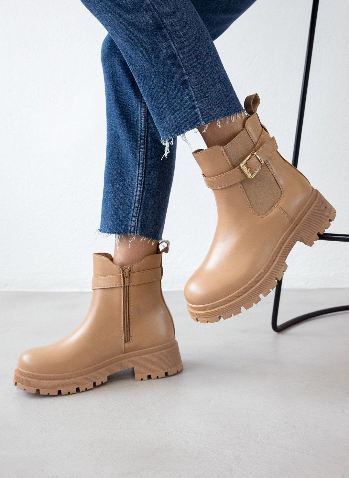 Taupe leather-look ankle boots with buckle strap and thick lug sole, worn on model, seated view