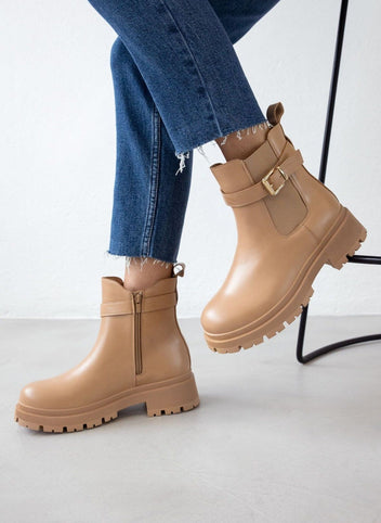 Taupe leather-look ankle boots with buckle strap and thick lug sole, worn on model, seated view