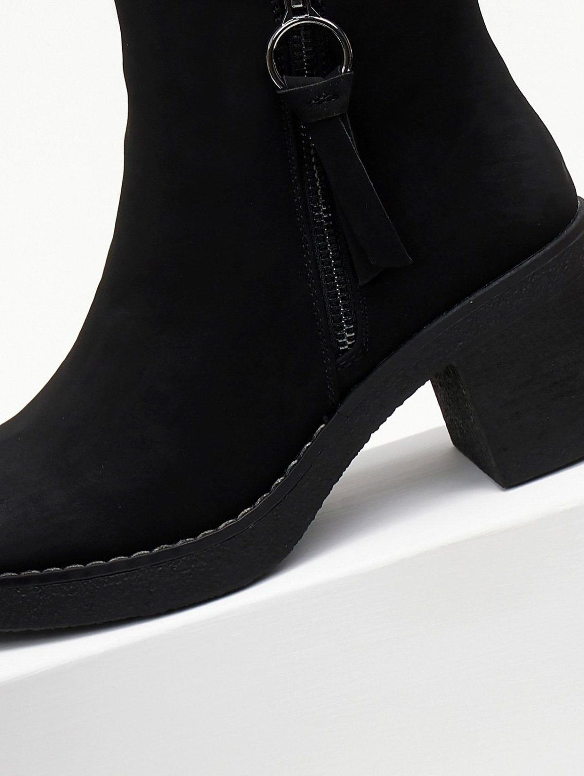 Close-up of the side zipper with ring pull and tassel on a black nubuck ankle boot with chunky sole