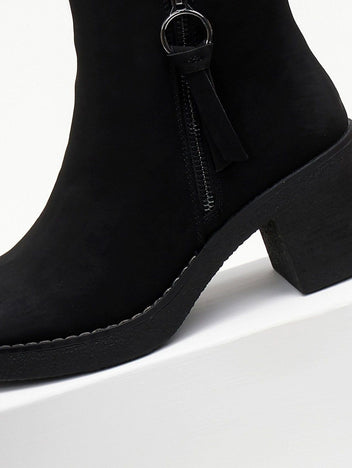 Close-up of the side zipper with ring pull and tassel on a black nubuck ankle boot with chunky sole