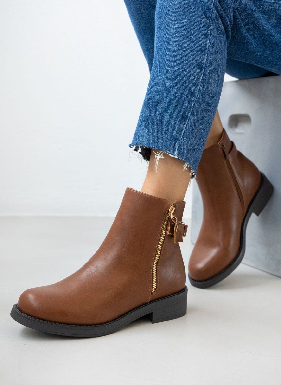 Tan leather-look ankle boots with gold zipper and low heel, worn on model, front view