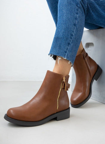 Tan leather-look ankle boots with gold zipper and low heel, worn on model, front view
