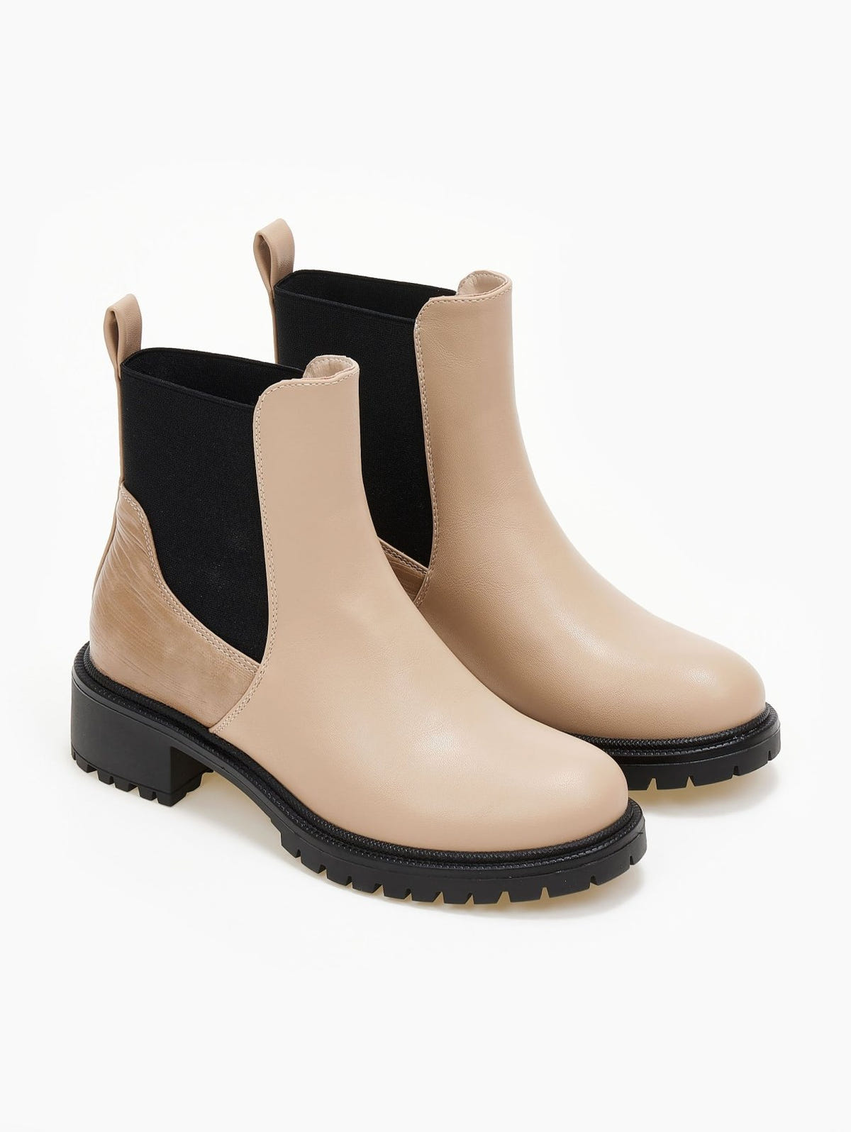 Pair of beige Chelsea ankle boots with black elastic gussets, pull tabs and chunky black sole, three-quarter view