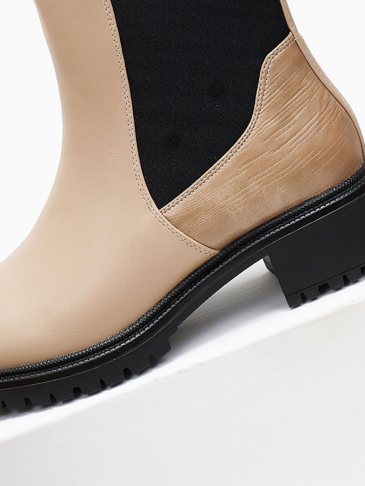 Close-up of beige Chelsea boot with black elastic gusset, embossed heel panel and black block heel