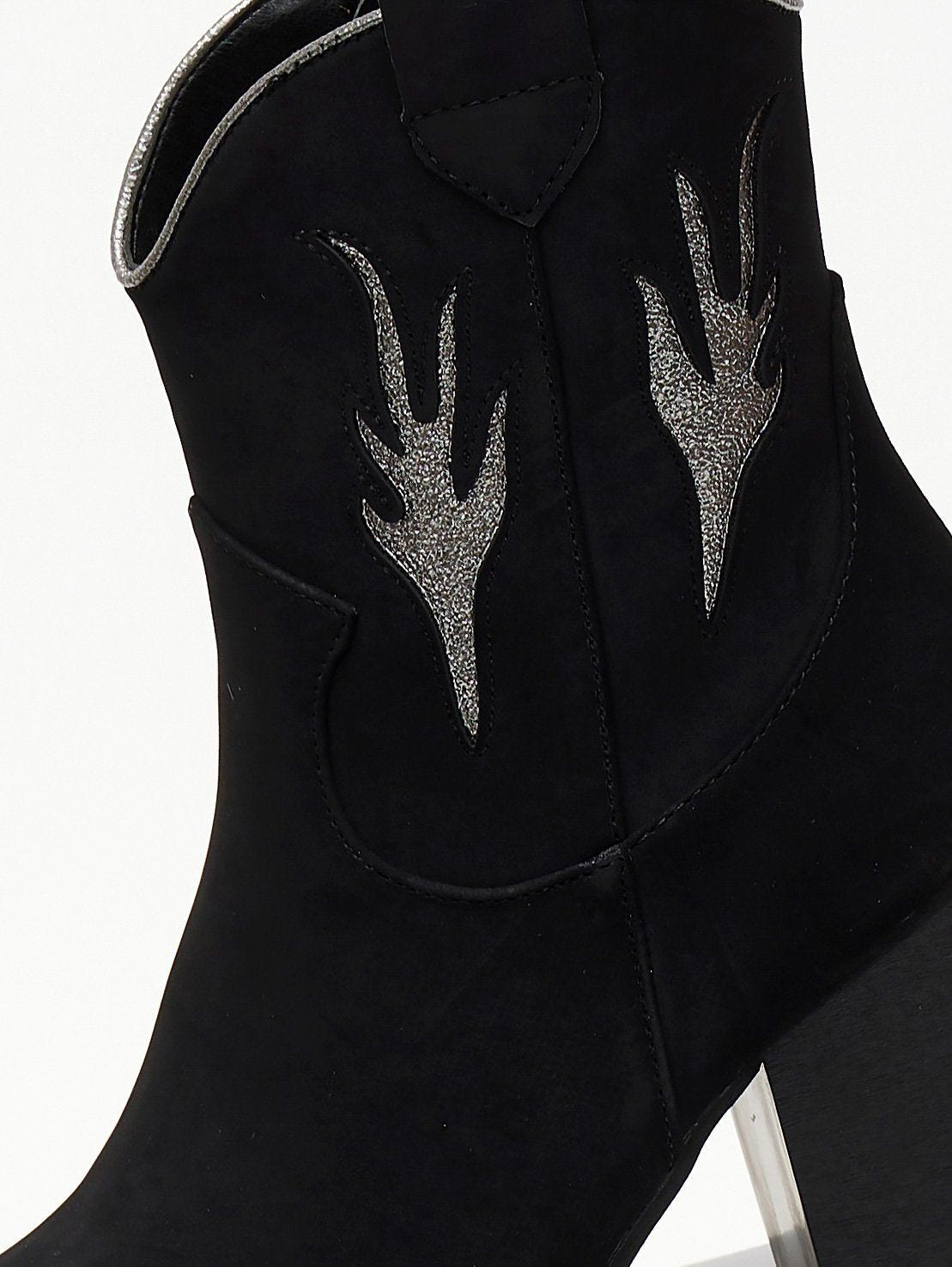 Close-up of silver metallic flame appliques on a black suede cowboy boot shaft with pull tab