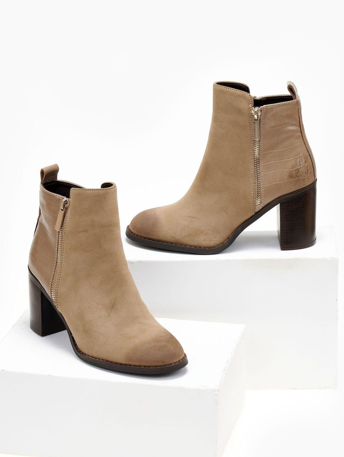 Pair of taupe suede ankle boots with croc-embossed back panel, side zip and block heel, shown on white blocks