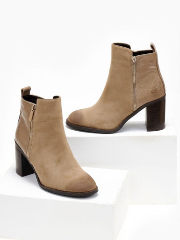 Pair of taupe suede ankle boots with croc-embossed back panel, side zip and block heel, shown on white blocks